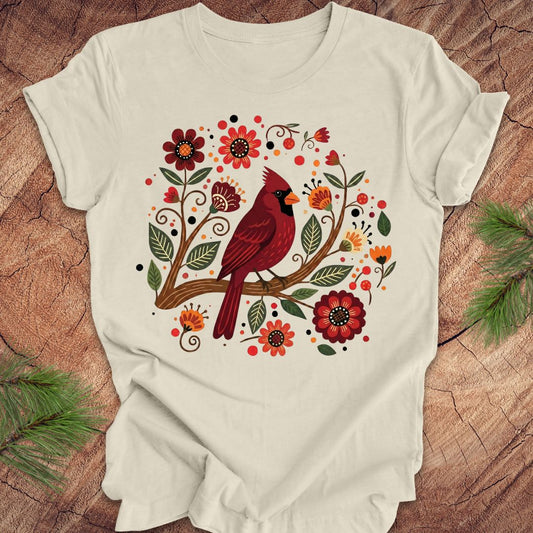 Beige t-shirt with a red cardinal and floral design on a wooden surface