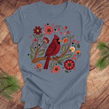 Blue t-shirt with a red cardinal and floral design on a wooden surface