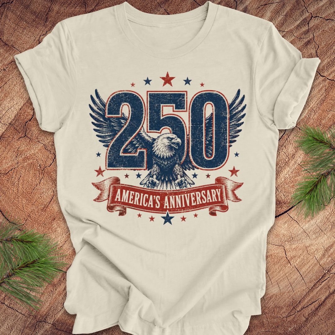 Beige t-shirt with '250 America's Anniversary' design featuring an eagle on a wooden surface.