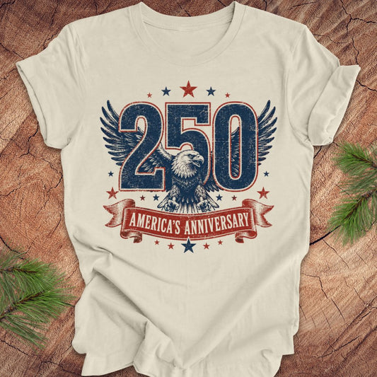 Beige t-shirt with '250 America's Anniversary' design featuring an eagle on a wooden surface.
