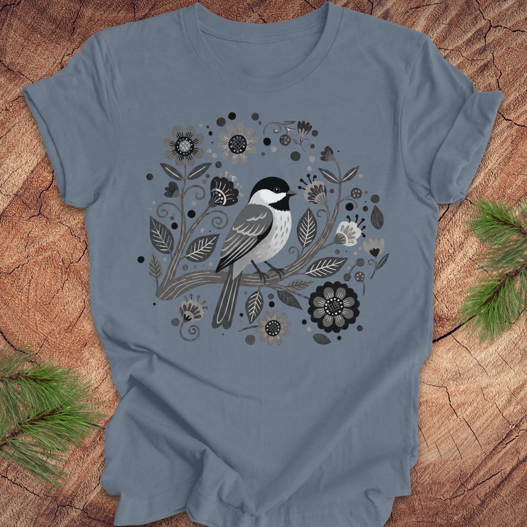 Blue t-shirt with a chickadee bird and floral design on a wooden surface