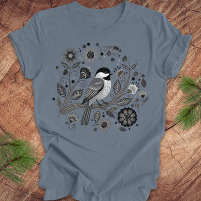 Blue t-shirt with a chickadee bird and floral design on a wooden surface