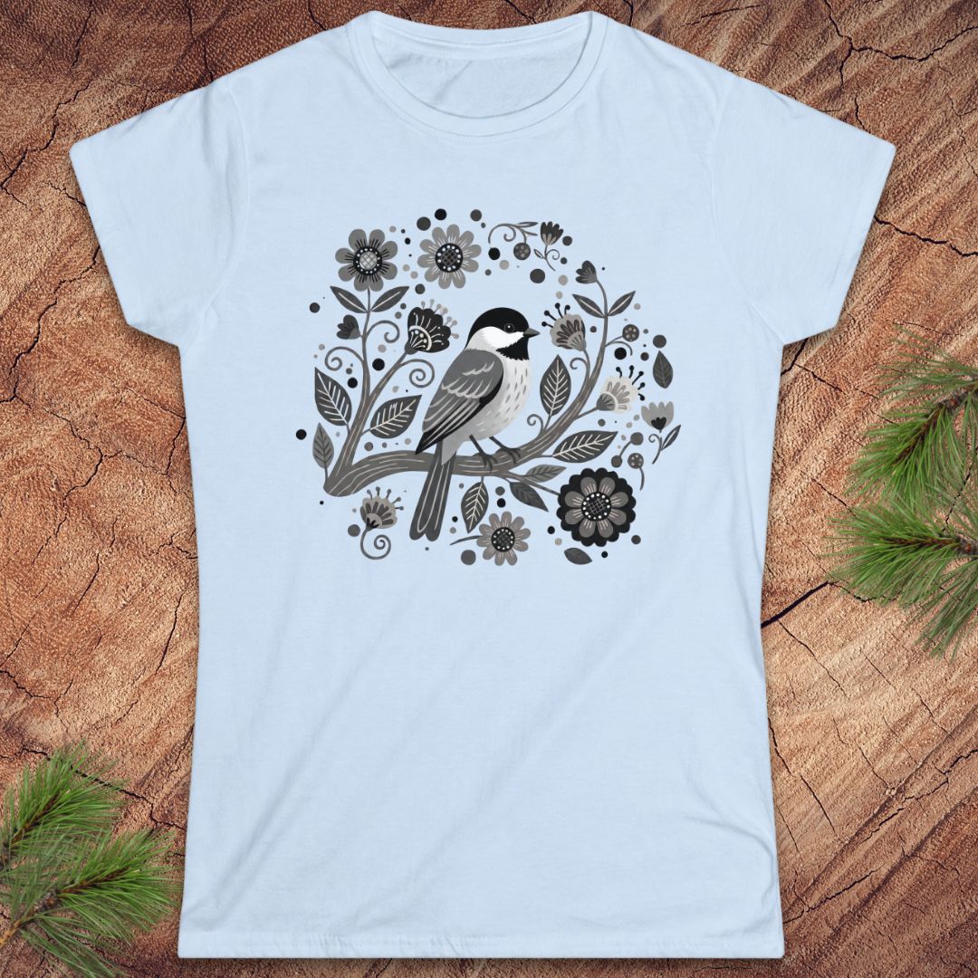 Light blue t-shirt with a chickadee bird and floral design on a wooden surface