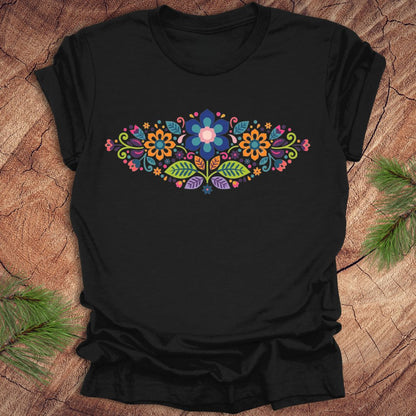 Black t-shirt with a vibrant floral pattern in an oval shape, on a wooden background.
