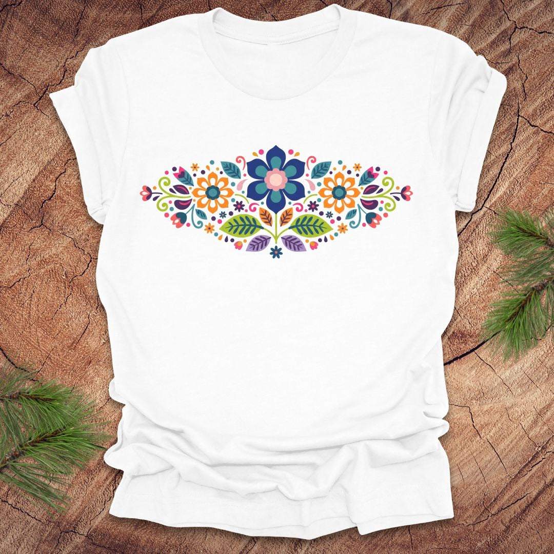 White t-shirt with a vibrant floral pattern in an oval shape, on a wooden background.