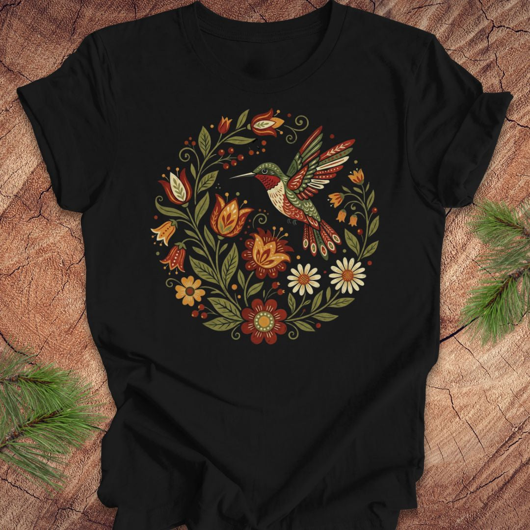 Black t-shirt with a colorful hummingbird and floral design on a wooden surface.