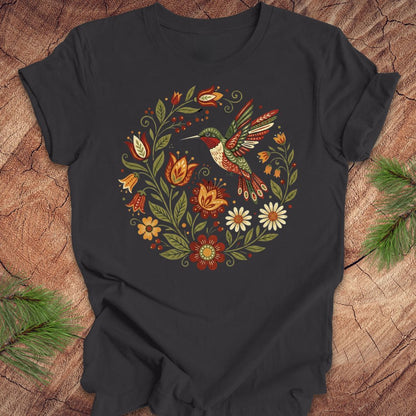 Dark gray t-shirt with a colorful hummingbird and floral design on a wooden surface.