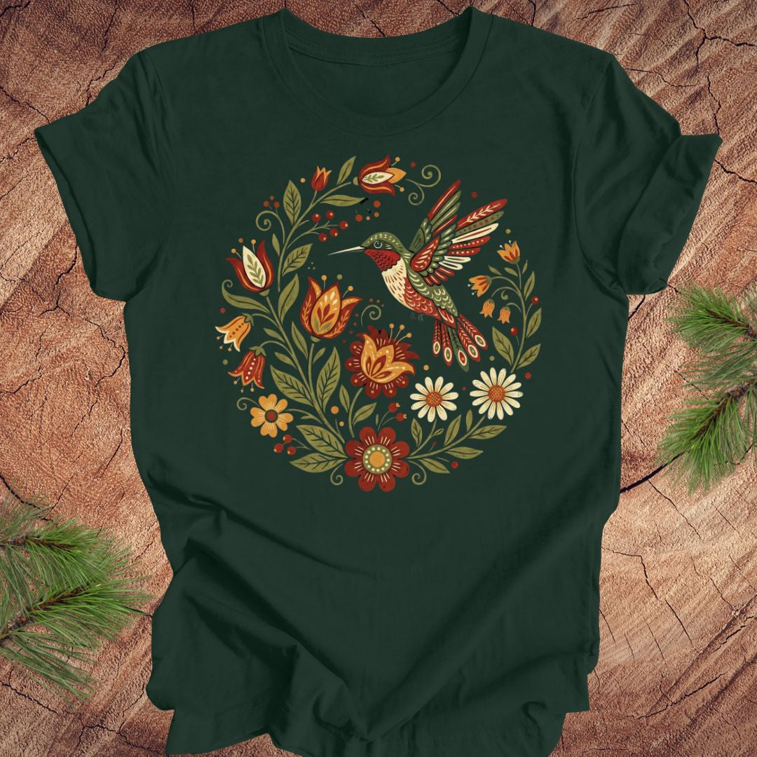 Green t-shirt with a colorful hummingbird and floral design on a wooden surface.