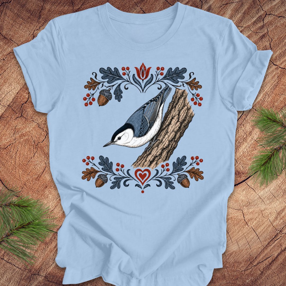 Light blue t-shirt with a nuthatch and flower design on a wooden surface