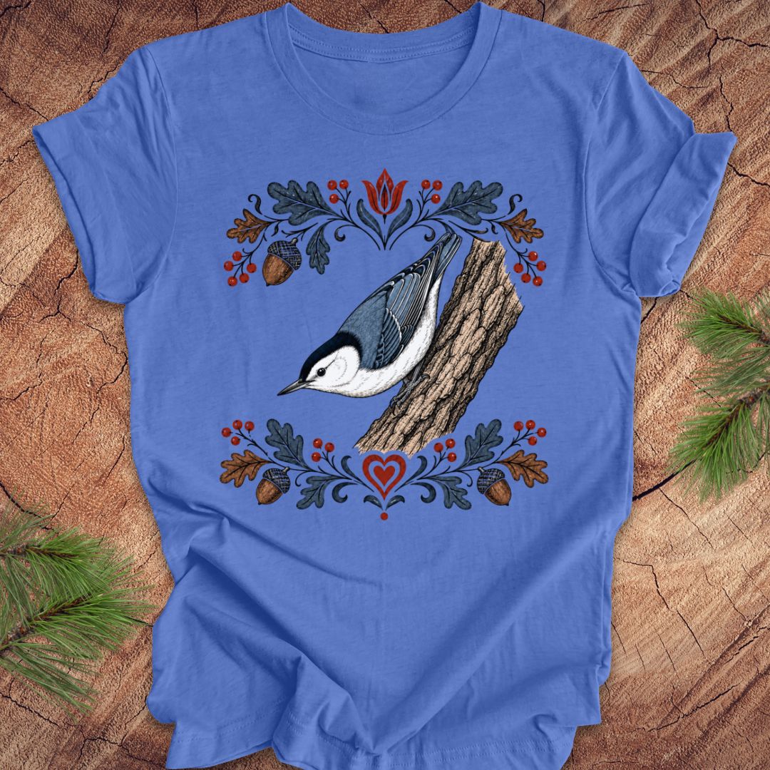 Blue t-shirt with a nuthatch and flower design on a wooden surface