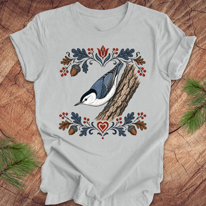 Gray t-shirt with a nuthatch and flower design on a wooden surface