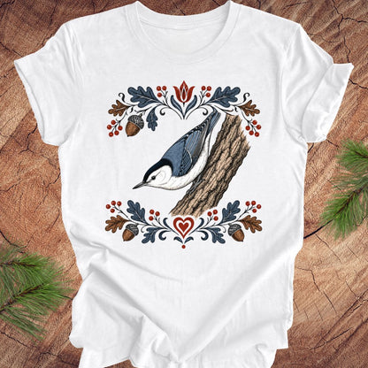 White t-shirt with a nuthatch and flower design on a wooden surface