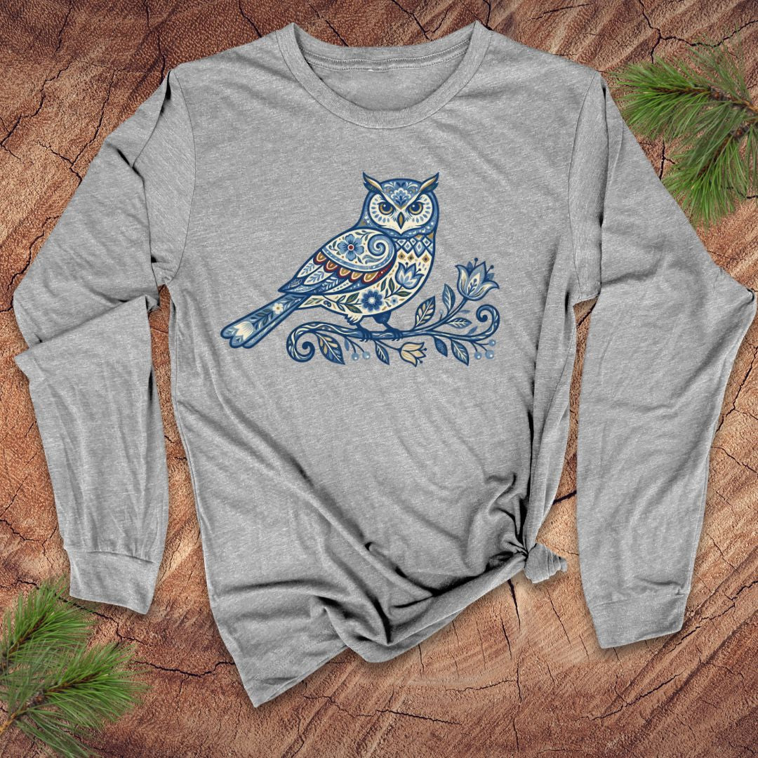 Gray long-sleeve shirt with a blue folk art floral owl design on a wooden surface.