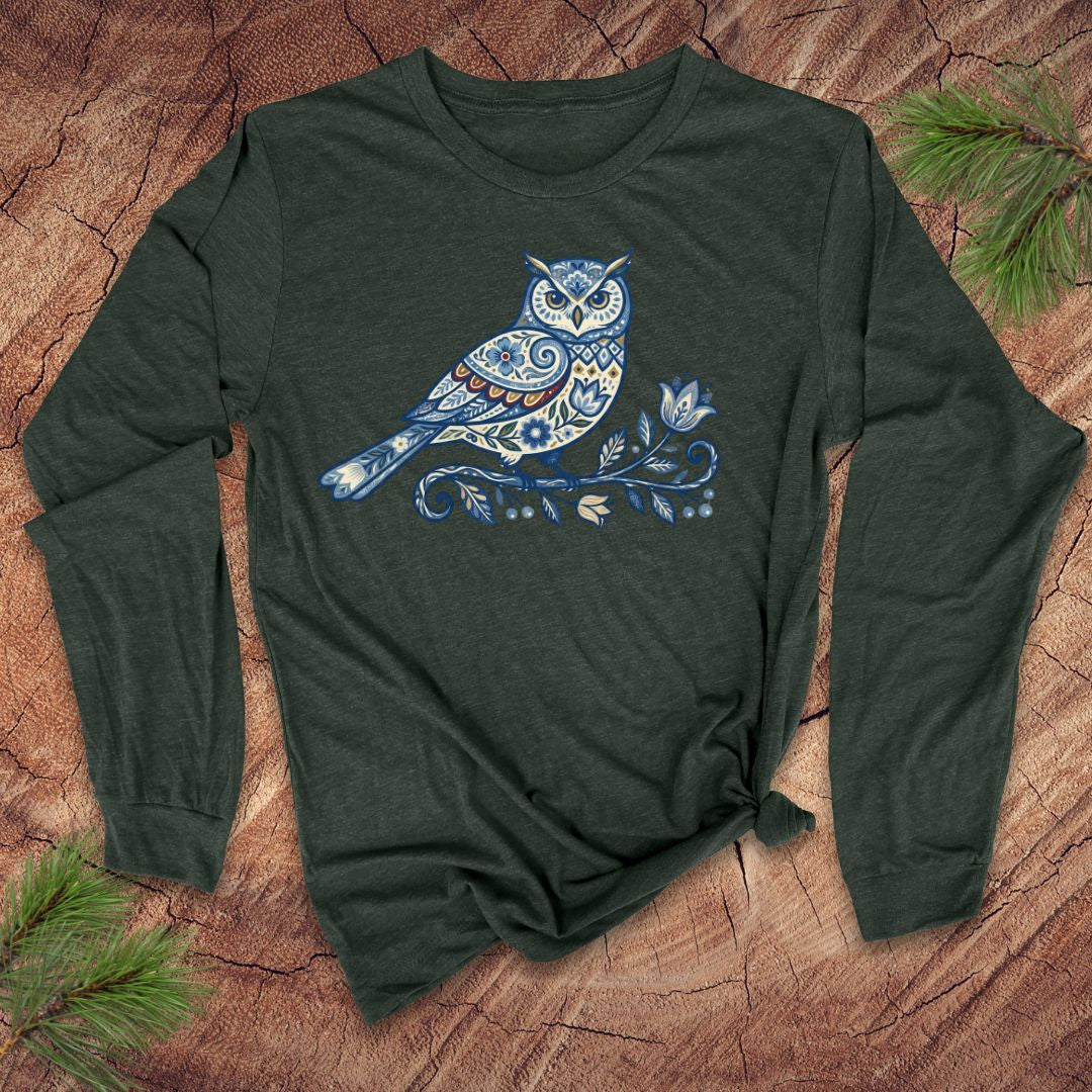 Green long-sleeve shirt with a blue folk art floral owl design on a wooden surface.
