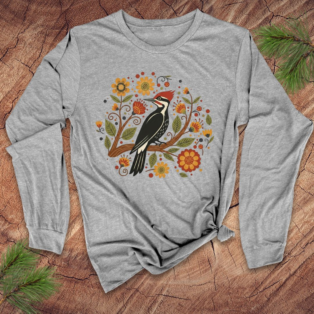 Gray long sleeve t-Shirt with a pileated woodpecker on a branch surrounded by folk art flowers on a wood background.