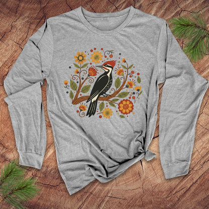 Gray long sleeve t-Shirt with a pileated woodpecker on a branch surrounded by folk art flowers on a wood background.