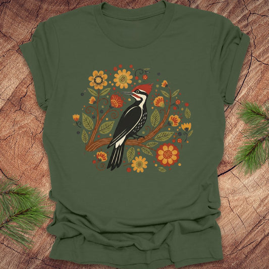 Green T-Shirt with a pileated woodpecker on a branch surrounded by folk art flowers on a wood background.