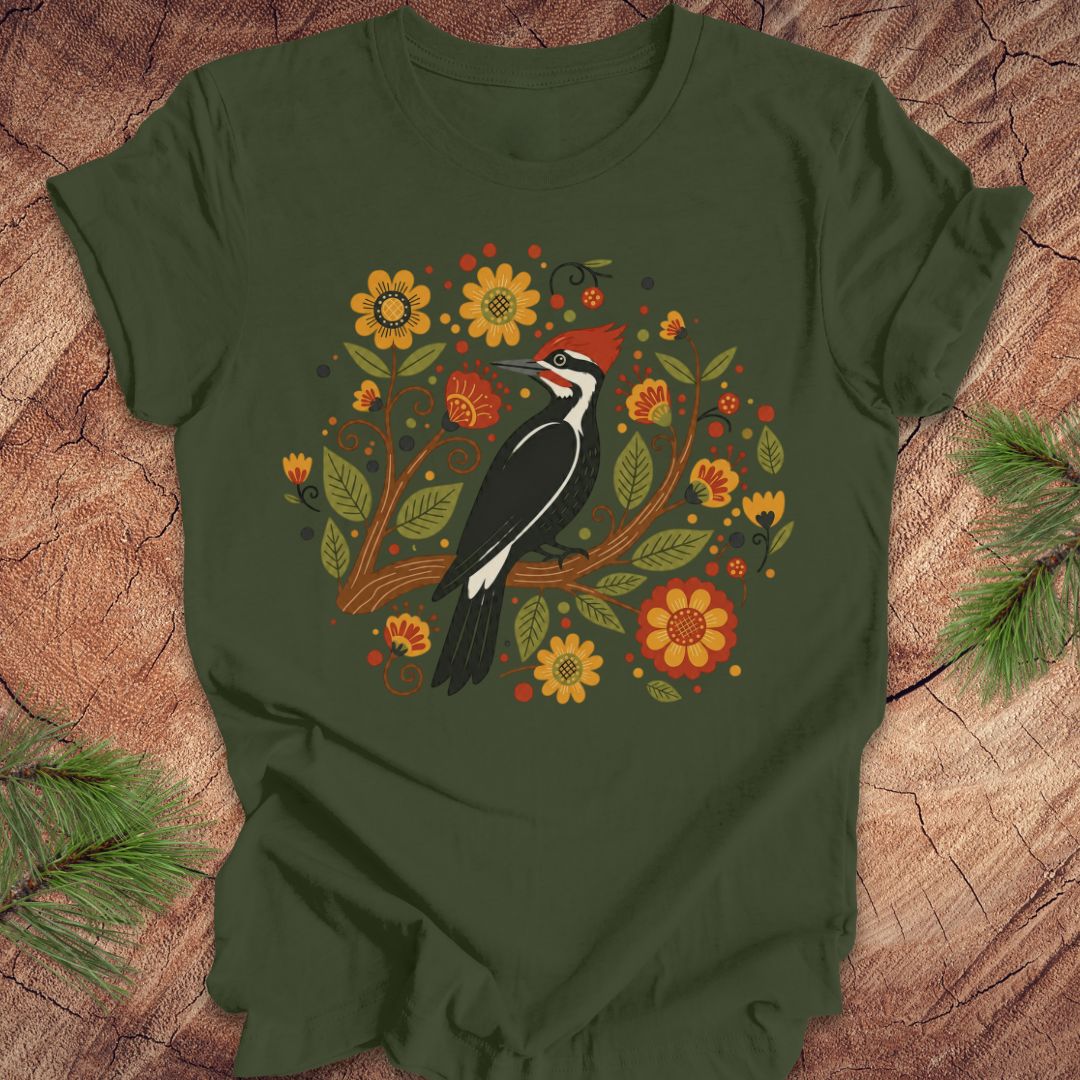 Green t-shirt with a woodpecker and floral design on a wooden surface