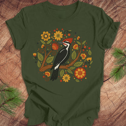 Green t-shirt with a woodpecker and floral design on a wooden surface