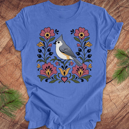 Blue t-shirt with a titmouse and floral design on a wooden surface
