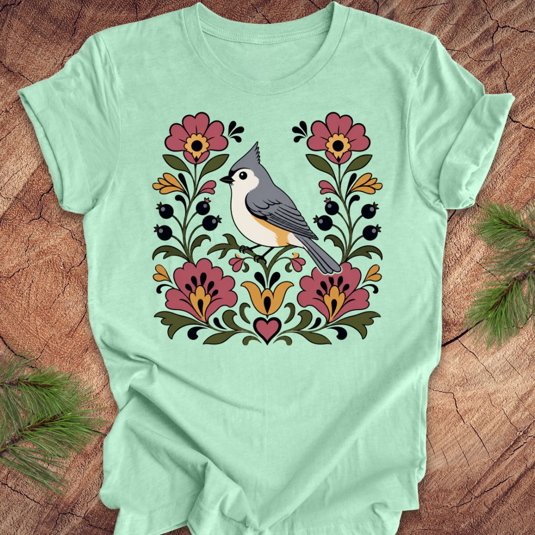 Mint green t-shirt with a titmouse and floral design on a wooden surface