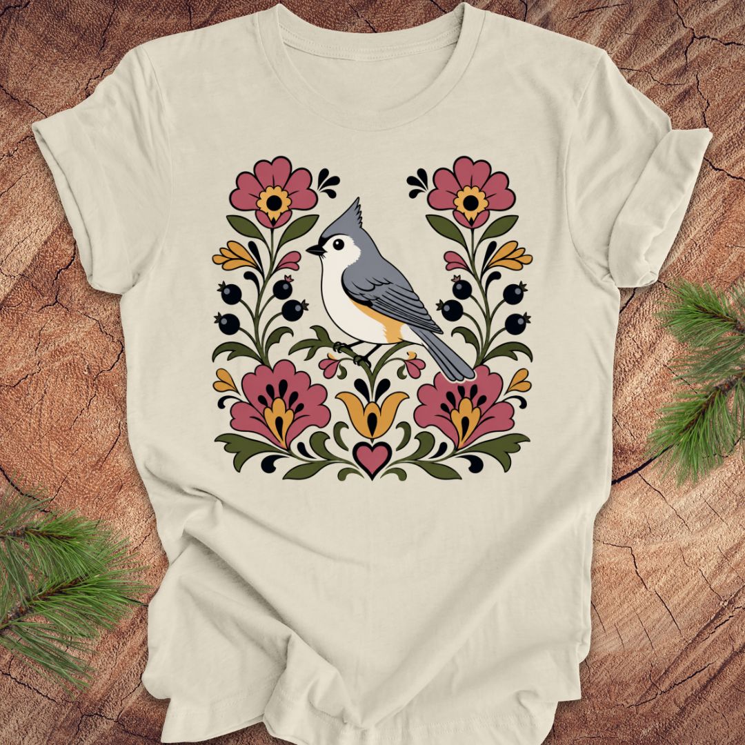 Beige t-shirt with a titmouse and floral design on a wooden surface