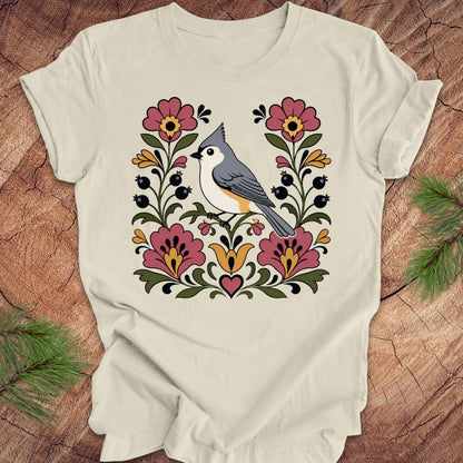 Beige t-shirt with a titmouse and floral design on a wooden surface