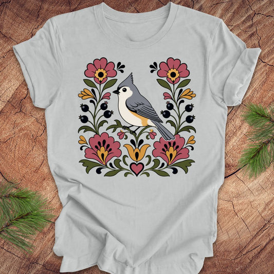 Gray t-shirt with a titmouse and floral design on a wooden surface