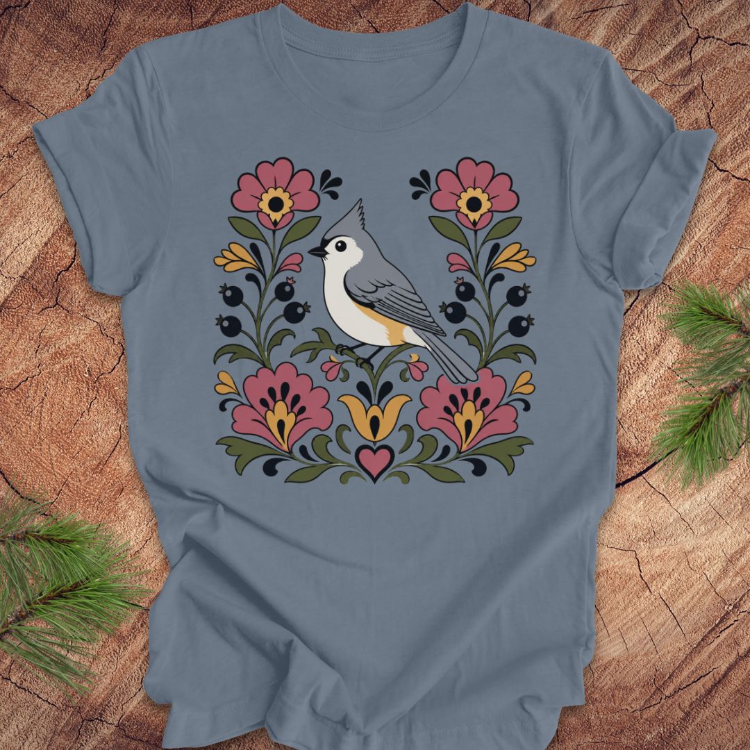 Blue t-shirt with a titmouse and floral design on a wooden surface