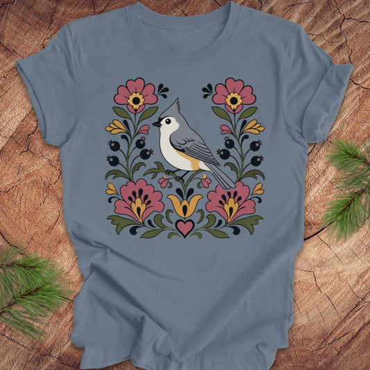 Blue t-shirt with a titmouse and floral design on a wooden surface