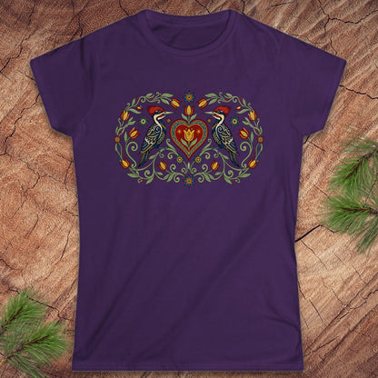 Purple t-shirt with a decorative design featuring birds and a heart on a wooden surface.