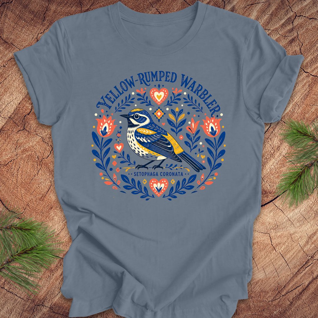 Blue t-shirt with a folk art yellow rumped warbler design on a wood background.