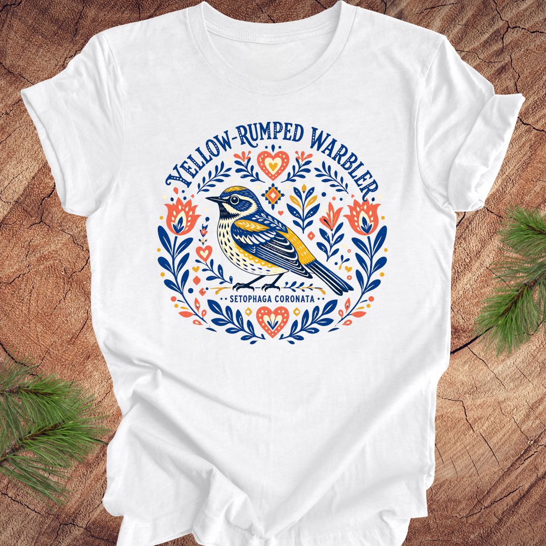 White t-shirt with a folk art yellow rumped warbler design on a wood background.