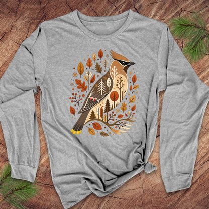 A heather gray long-sleeve t-shirt with a detailed graphic of a cedar woodpecker surrounded by autumn leaves and pine trees, laid flat on a rustic wood background with pine needles.