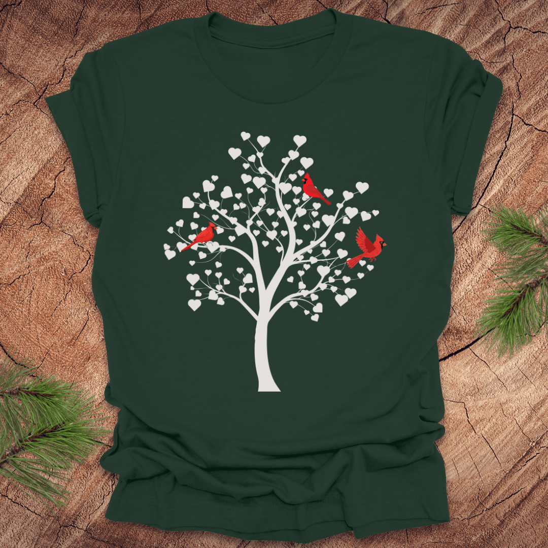 Forest green t-shirt with a tree design featuring cardinals and white hearts on a wooden surface.