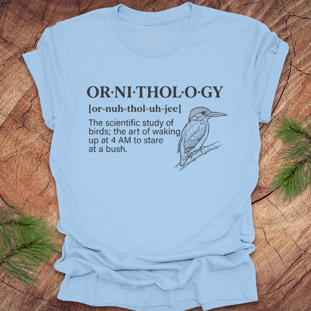 Baby blue t-shirt with a funny version of the definition of the word ornithology, with a picture of a bird, on a wood background.