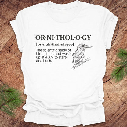 White t-shirt with a funny version of the definition of the word ornithology, with a picture of a bird, on a wood background.