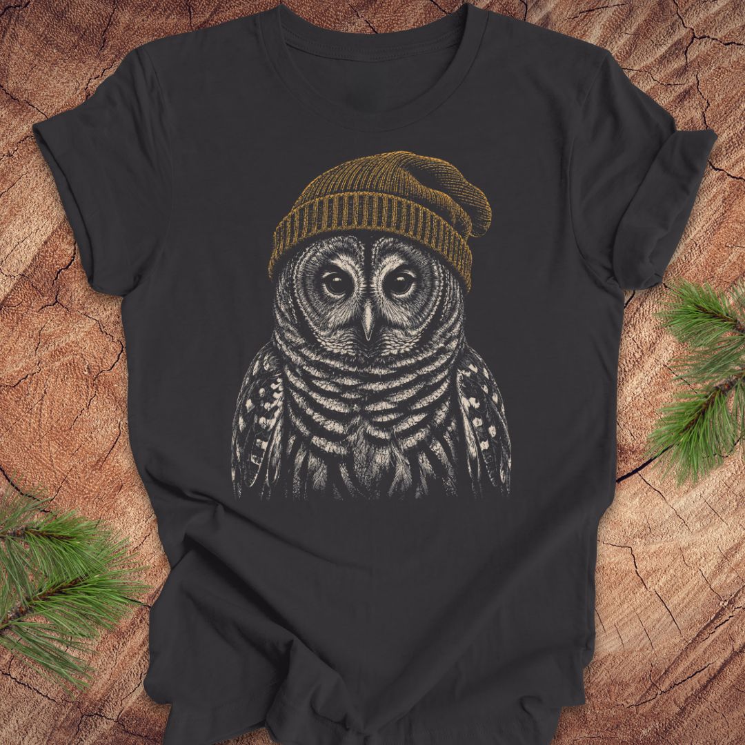 Dark gray t-shirt with a barred owl wearing a beanie on a wooden surface.