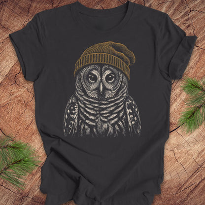 Dark gray t-shirt with a barred owl wearing a beanie on a wooden surface.