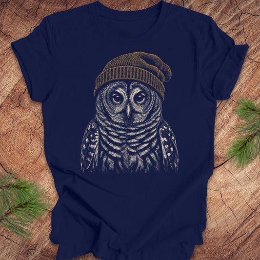 Navy blue t-shirt with a barred owl wearing a beanie on a wooden surface.
