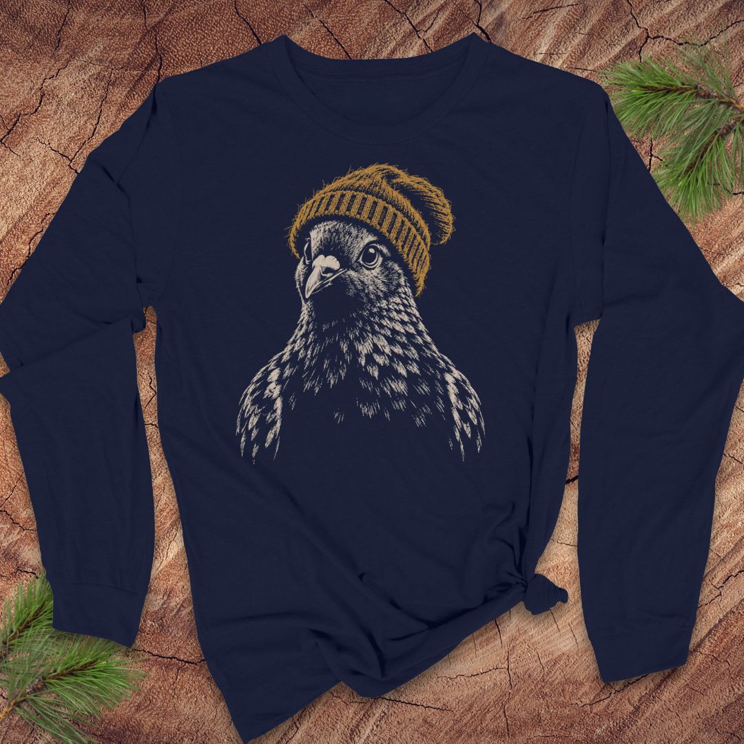 A navy blue long-sleeve t-shirt with a graphic of a bird of prey wearing a yellow knit beanie, laid flat on a rustic wood background with pine branches.
