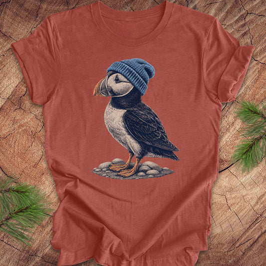 Red t-shirt with a puffin wearing a blue beanie on a wooden surface