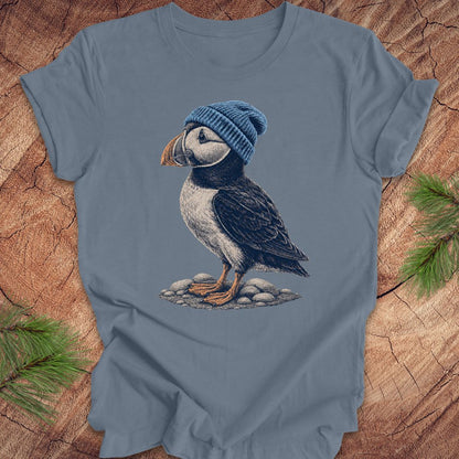 Blue t-shirt with a puffin wearing a blue beanie on a wooden surface.