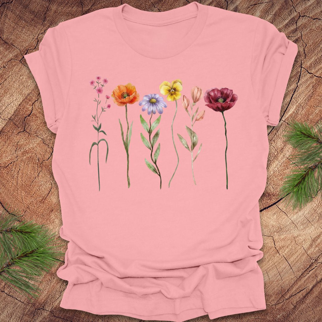 Pink t-shirt with colorful floral designs on a wooden surface