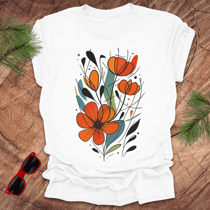 White t-shirt with orange floral design on a wooden surface with sunglasses and greenery.