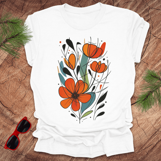 White t-shirt with orange floral design on a wooden surface with sunglasses and greenery.