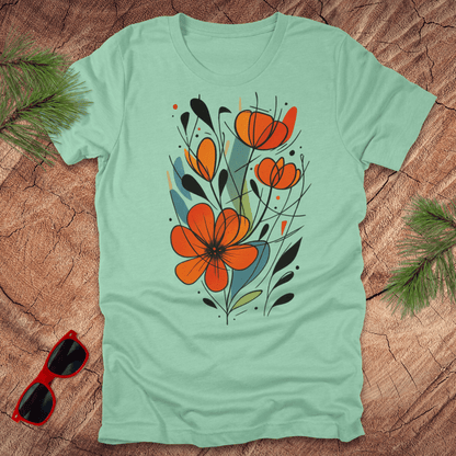 mint green t-shirt with orange floral design on a wooden surface with sunglasses and greenery.