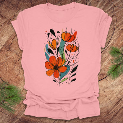 Pink t-shirt with a colorful floral design on a wooden surface