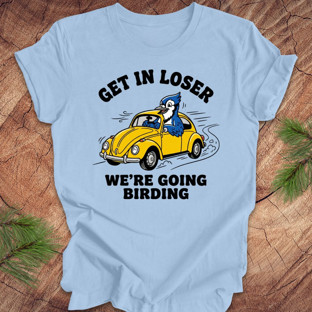 Light blue t-shirt with a graphic of a blue jay driving a yellow car and text on a wooden surface.