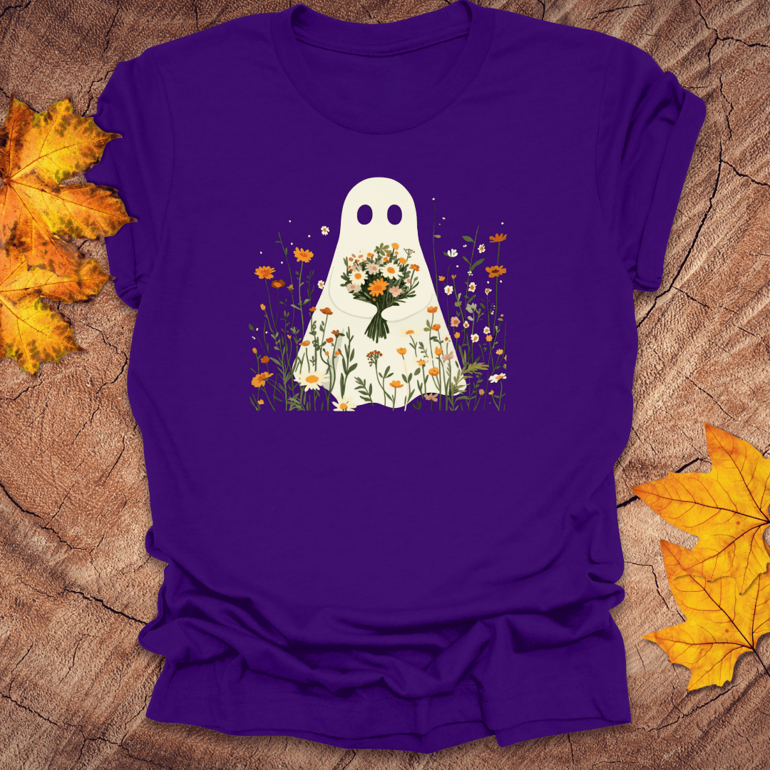Purple t-shirt with a ghost holding flowers design on a wooden surface with autumn leaves.